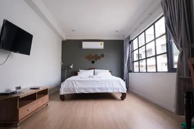 a bedroom with a bed and a flat screen tv at Pann Residence in Bangkok
