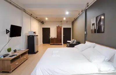 a bedroom with a large white bed and a tv at Pann Residence in Bangkok