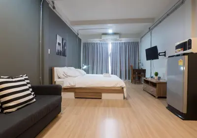 a bedroom with a bed and a couch and a tv at Pann Residence in Bangkok