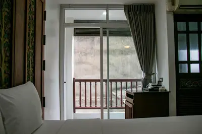 a bedroom with a bed and a view of a balcony at Lamphu Tree House Boutique Hotel in Bangkok