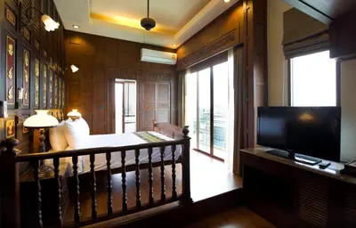 a living room with a balcony with a television at Lamphu Tree House Boutique Hotel in Bangkok