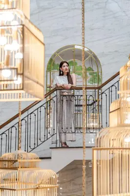 a woman leaning on a railing while talking on a cell phone at The Salil Hotel Sukhumvit 57 - Thonglor in Bangkok