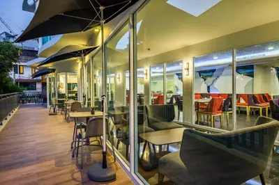 a restaurant with tables and chairs and windows at Anajak Bangkok Hotel - SHA Plus in Bangkok