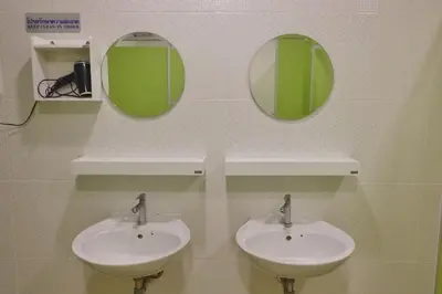 a bathroom with two sinks and two mirrors on the wall at Mahannop Hostel in Bangkok