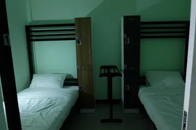 two beds in a room with green walls at Mahannop Hostel in Bangkok