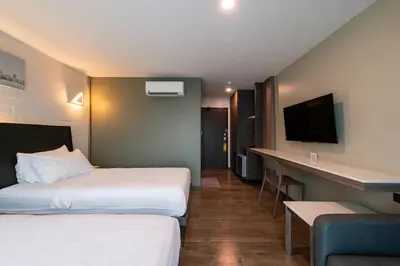 a hotel room with two beds and a desk at BB House Khlong Tan บีบีเฮ้าส์ คลองตัน in Bangkok