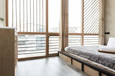 a bedroom with a bed and large windows at Vann Bangkok Boutique House in Bangkok