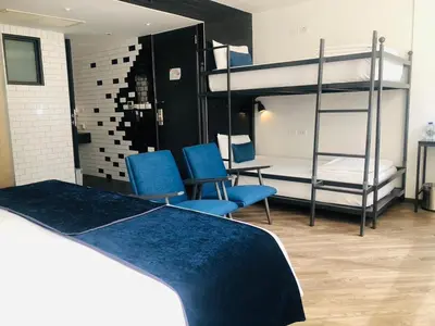 a bedroom with two bunk beds and two blue chairs at Klub Hotel Bangkok in Bangkok