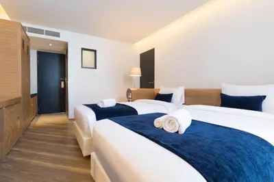 a hotel room with two beds with blue sheets at Klub Hotel Bangkok in Bangkok
