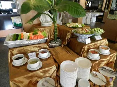 a buffet with plates and bowls of food on tables at Niran Grand Hotel in Bangkok