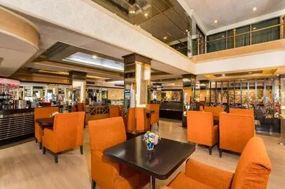 a restaurant with orange chairs and a black table at Niran Grand Hotel in Bangkok