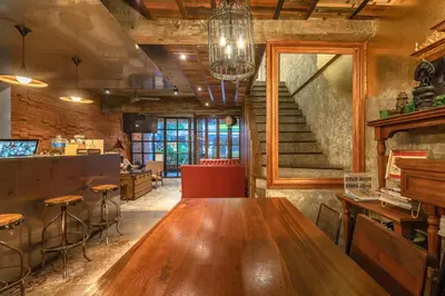 a large wooden table in a room with a staircase at Siam Plug In Hostel in Bangkok