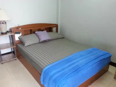 a bedroom with a bed with a blue blanket on it at Roong-Arun Apartment in Bangkok