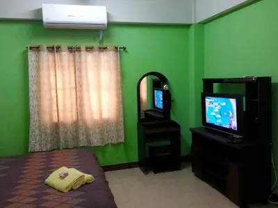 a green bedroom with a bed and a television at Roong-Arun Apartment in Bangkok