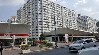 a large building with cars parked in front of it at Popular Condo C4 in Nonthaburi