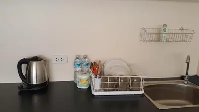 a kitchen counter with a sink and a dish drying rack at Popular Condo C4 in Nonthaburi