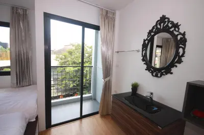 a bedroom with a bed and a mirror and a window at Darin Hostel in Bangkok