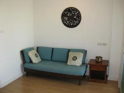 a blue couch in a room with a clock on the wall at Bangkok view in Pinklao in Bangkok