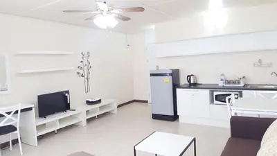 a kitchen and living room with white cabinets and a ceiling fan at Popular Condo C6 in Nonthaburi