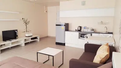 a living room with a couch and a kitchen at Popular Condo P1 in Nonthaburi