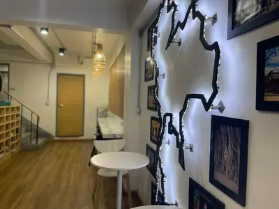 a room with a table and a wall with pictures at ORA Hostel Bangkok in Bangkok