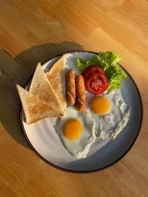 a plate of eggs and sausage and toast on a table at ORA Hostel Bangkok in Bangkok