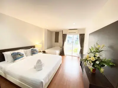 a bedroom with a large white bed and a vase of flowers at 14 Place Sukhumvit Suites in Bangkok