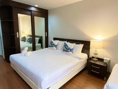 a bedroom with a large white bed and a mirror at 14 Place Sukhumvit Suites in Bangkok