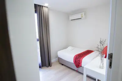 a small bedroom with a bed and a table at Hope Land Hotel Sukhumvit 8 in Bangkok
