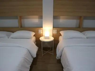 a room with two beds and a table with a lamp at Boon Street Hostel in Bangkok