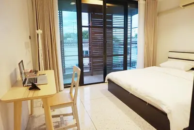 a bedroom with a bed and a desk with a laptop at Boon Street Hostel in Bangkok