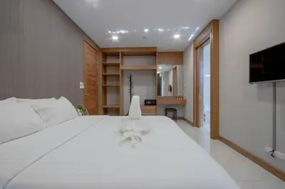 a bedroom with a white bed and a television at Kepler Residence Bangkok in Bangkok