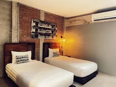 a bedroom with two beds and a brick wall at Yotaka The Hostel in Bangkok