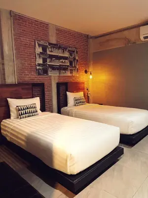 two beds in a bedroom with a brick wall at Yotaka The Hostel in Bangkok