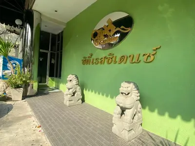 a green building with two statues in front of it at City Residence in Bangkok