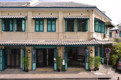 a building with green doors and windows on a street at Neighbor Phuthon in Bangkok