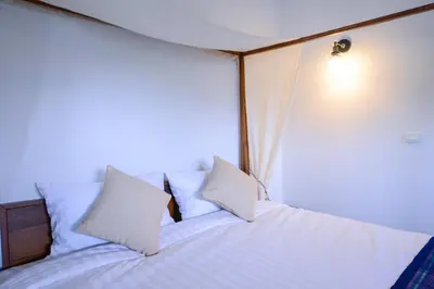 a bed in a room with white sheets and pillows at Neighbor Phuthon in Bangkok