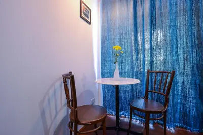 a table and two chairs and a vase with a yellow flower at Neighbor Phuthon in Bangkok