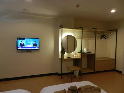 a living room with a tv on the wall and a mirror at Klean Residence Hotel in Bangkok