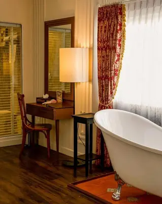 a bathroom with a bath tub next to a desk and a chair at Siam Champs Elyseesi Unique Hotel in Bangkok