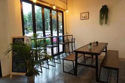 a dining room with tables and chairs and a window at Krit Hostel in Bangkok