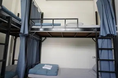 two bunk beds in a room with blue curtains at Krit Hostel in Bangkok