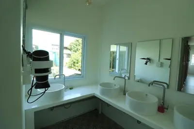 a bathroom with three sinks and a large window at Krit Hostel in Bangkok