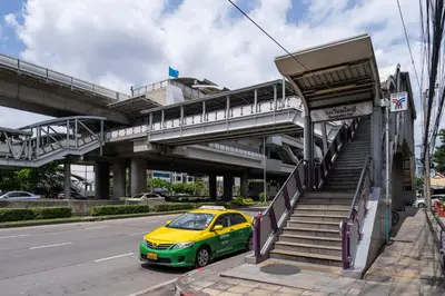 a yellow and green car parked at a bus stop at W Station in Bangkok