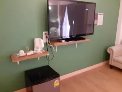a flat screen tv on a green wall in a room at Sudyod Apartment in Bangkok