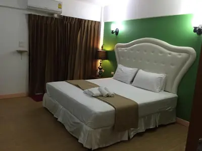 a bedroom with a white bed with a green wall at Sudyod Apartment in Bangkok