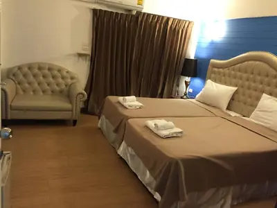 a hotel room with two beds and a chair at Sudyod Apartment in Bangkok
