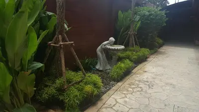a garden with a statue of a woman in a fountain at Sudyod Apartment in Bangkok