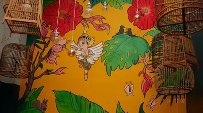 a wall with a painting of flowers and bird cages at Kinnon Deluxe Hostel Coworking Cafe in Bangkok