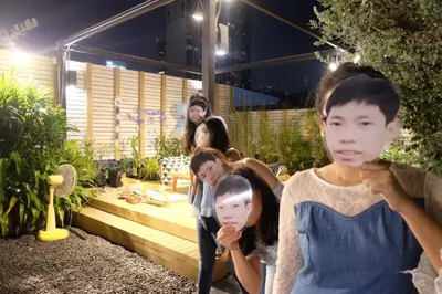 a group of people standing in a garden at night at Kinnon Deluxe Hostel Coworking Cafe in Bangkok
